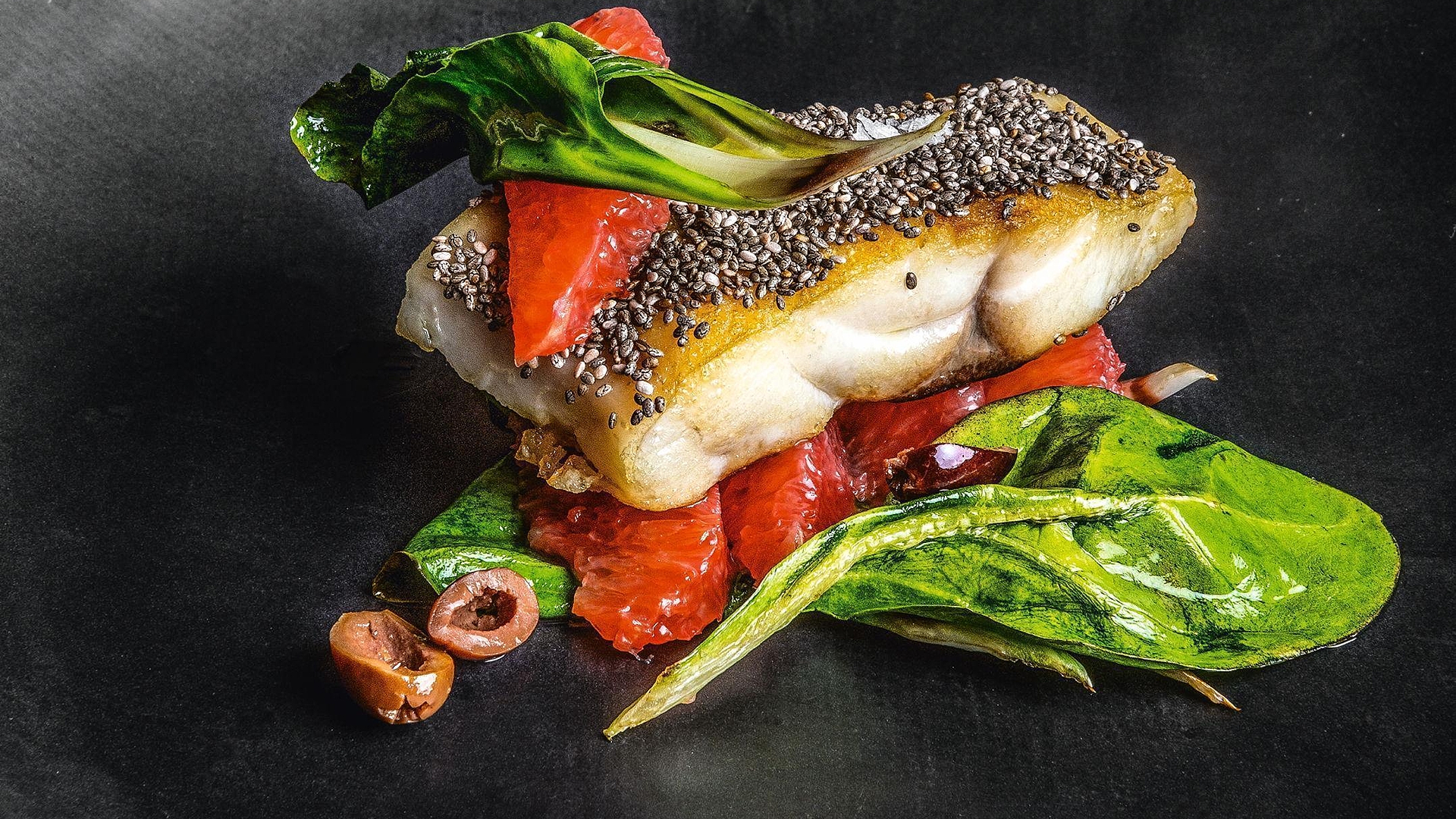 Hake in a chia seed crust with pink grapefruit, taggiasca olives and chard