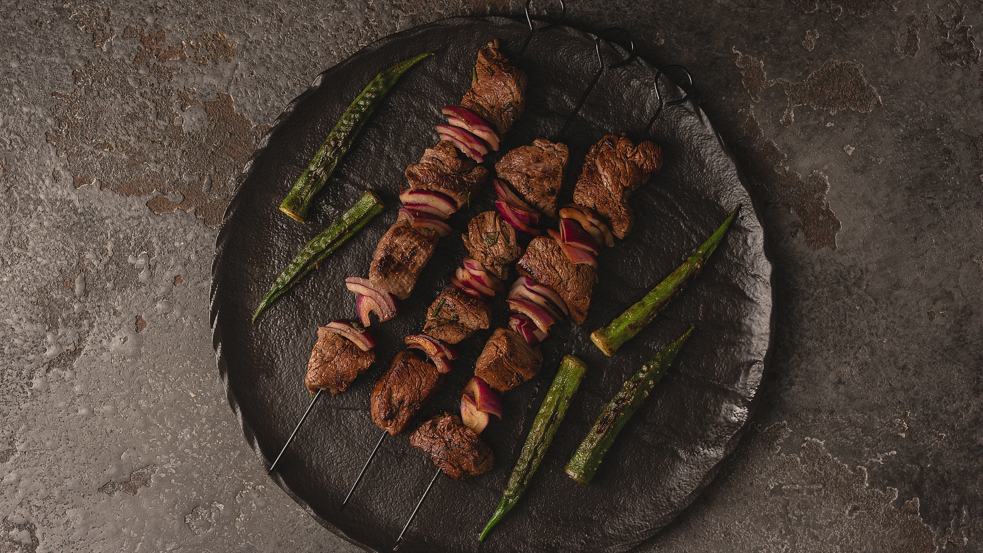 Beef skewers with red onion and okra